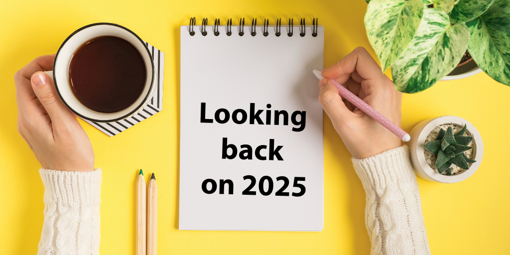 A graphic of a person writing on a notepad with the words "Looking back on 2025." The background is yellow and there is a coffee cup and a plant in the background